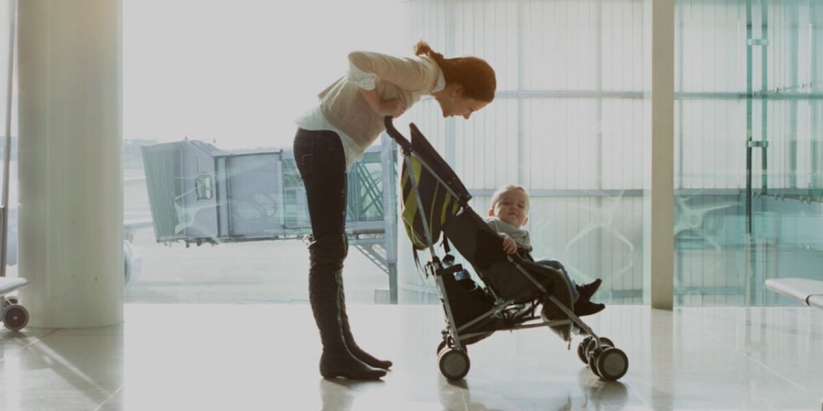 A mother leaning over a rental stroller at an airport gate