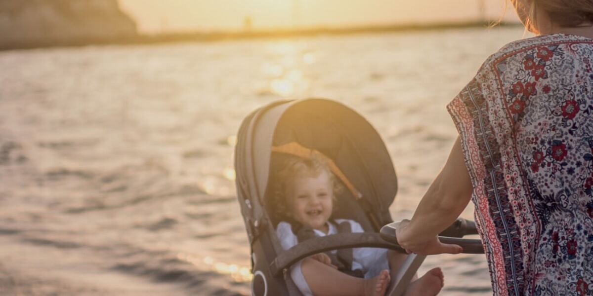 A mother pushing a rental stroller along a beach at sunset