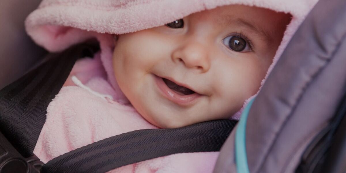 A smiling baby buckled into one of our rental car seats